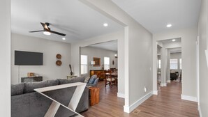 A spacious living area with a gray sectional sofa, wooden coffee table, and a ceiling fan. A dining area with wooden chairs and a table is visible in the background. - 3325: Bright Urban Comfort by JZ Vacation Rentals (St. Louis)