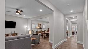 A spacious living room with a gray sofa, patterned armchair, and a dining area with wooden furniture. - 3323: Uptown Elegant Escape by JZ Vacation Rentals (St. Louis)