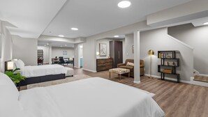 A spacious hotel room with two beds, a desk, a chair, a bookshelf, and a staircase. - 3323: Uptown Elegant Escape by JZ Vacation Rentals (St. Louis)