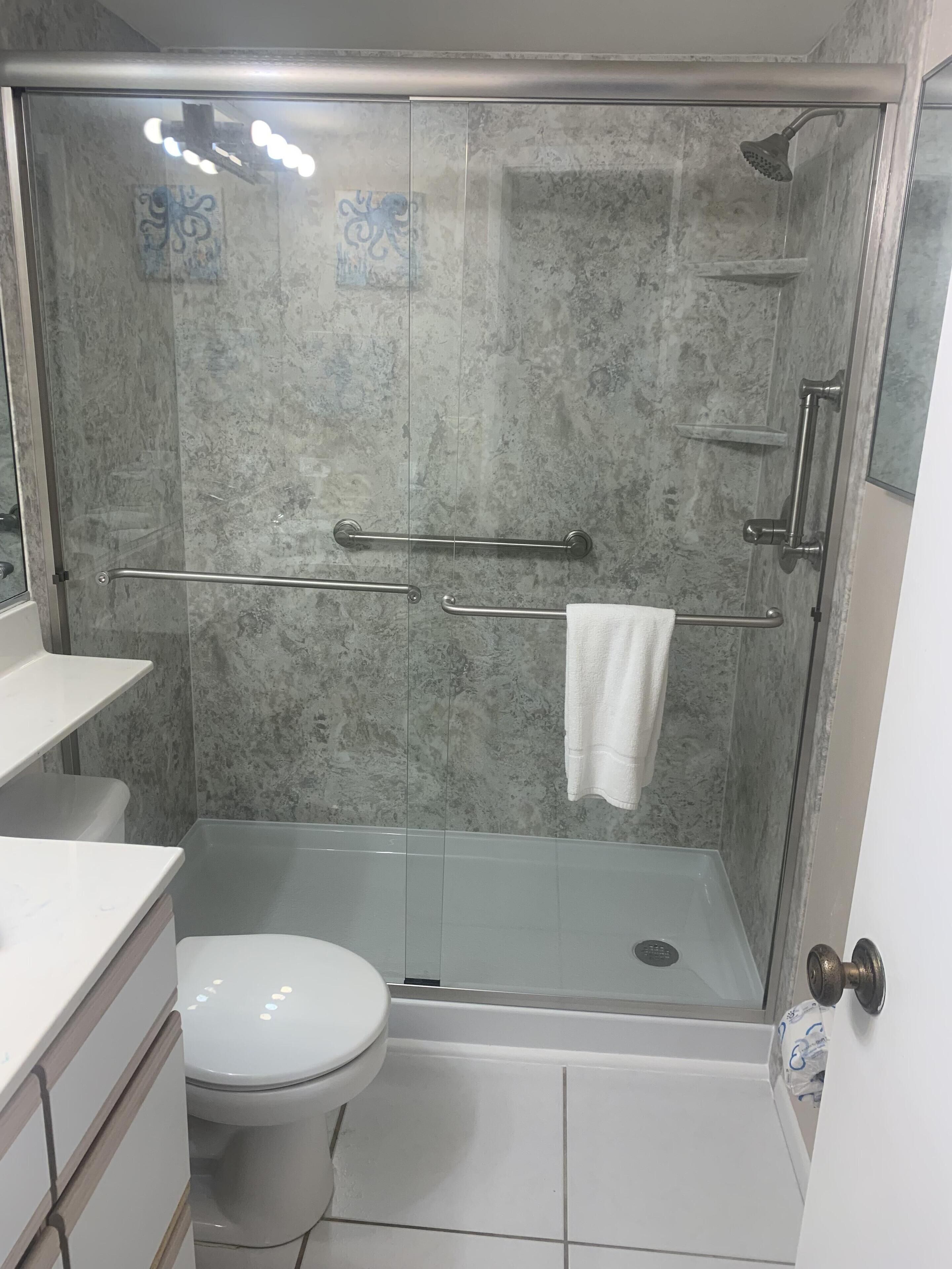 A bathroom with a glass-enclosed shower, a white toilet, and a white sink.