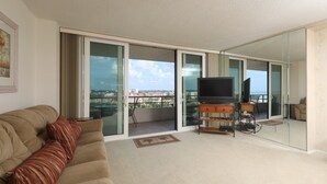 A balcony with a TV, a sofa, and a view of the city. - Anchorage Resort 9th Floor 2 Bedroom Condo With Balcony Gulf Views Poolbeach 0895 (Siesta Key)