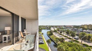 Een balkon met een glazen tafel, stoelen en een fles champagne.