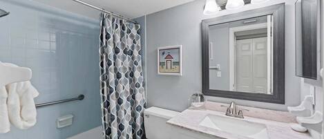 Un baño con bañera, inodoro, lavamanos y cortina de ducha.