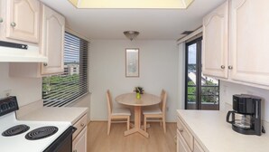 Una cocina con una mesa de comedor, sillas, una cafetera y vistas al exterior.