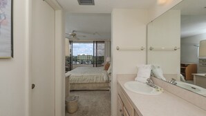 Habitación de hotel con cama, un espejo grande, lavamanos y vistas a edificios a través de la ventana.