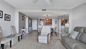 A modern living room with a sofa, armchairs, a dining table, and a kitchen in the background. - Anchorage Resort Siesta Key 6th Floor 2 Bedroom Condo Beach Access 0890 (Siesta Key)