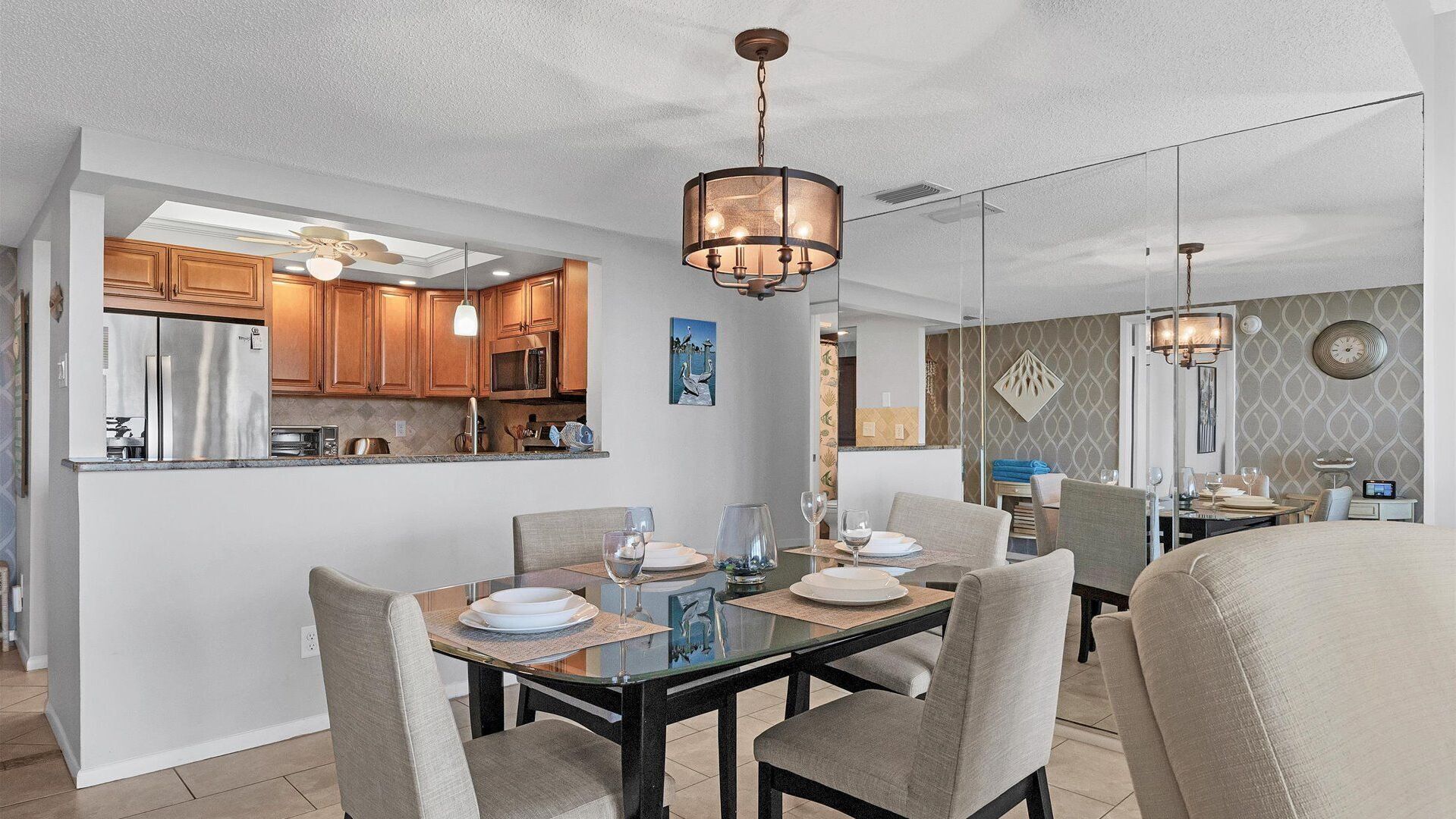 A modern dining area with a glass table, chairs, and a chandelier.