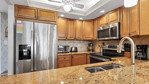 A kitchen with wooden cabinets, stainless steel appliances, granite countertops, and a ceiling fan. - Anchorage Resort Siesta Key 6th Floor 2 Bedroom Condo Beach Access 0890 (Siesta Key)