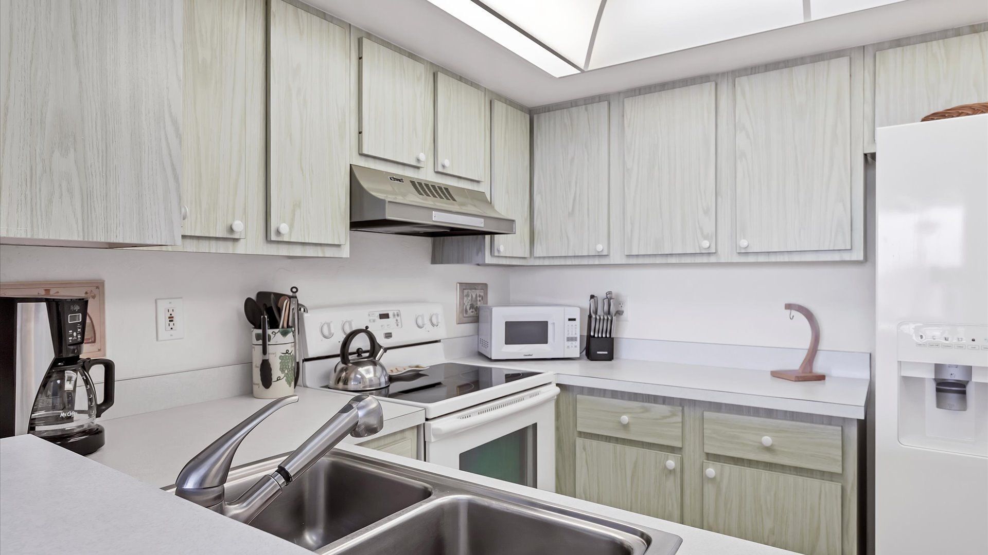Una cocina moderna con armarios blancos, electrodomésticos de acero inoxidable y un horno empotrado.