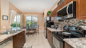 A compact kitchen with granite countertops, stainless steel appliances, and a dining area with a view of the outdoors. - Fp8157 - Windsor Palms Resort 4 Bedroom Home With Game Room (Kissimmee)