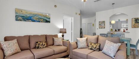 A living room with two sofas, a coffee table, and a ceiling fan.