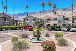 A hotel with a central fountain, surrounded by landscaped gardens, palm trees, and mountain views. - Farrell N79 (Palm Springs)