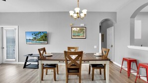 A dining room with a wooden table and chairs, a chandelier, and artwork on the walls. - Bf2301-301 (Kissimmee)