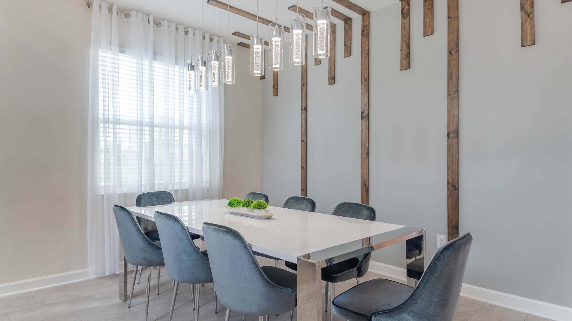 A modern dining room with a rectangular table, six chairs, and hanging pendant lights.