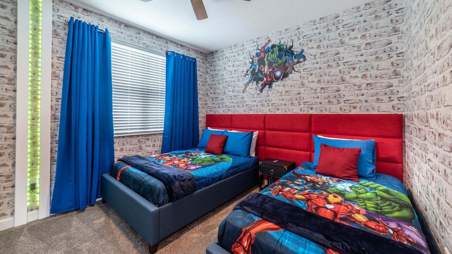 A bedroom with two beds, a brick-patterned wall, and a window with blue curtains.