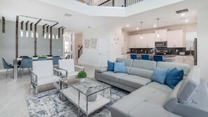 A modern living room with a sofa, chairs, a coffee table, and a dining area with a table and chairs. - Wsb610 (Kissimmee)