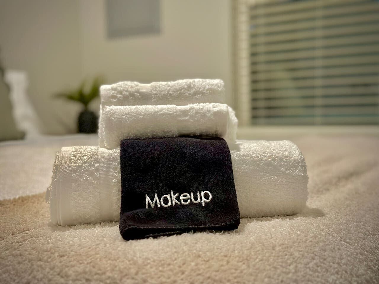 A set of towels with a black tag labeled "Makeup" on a carpeted floor.