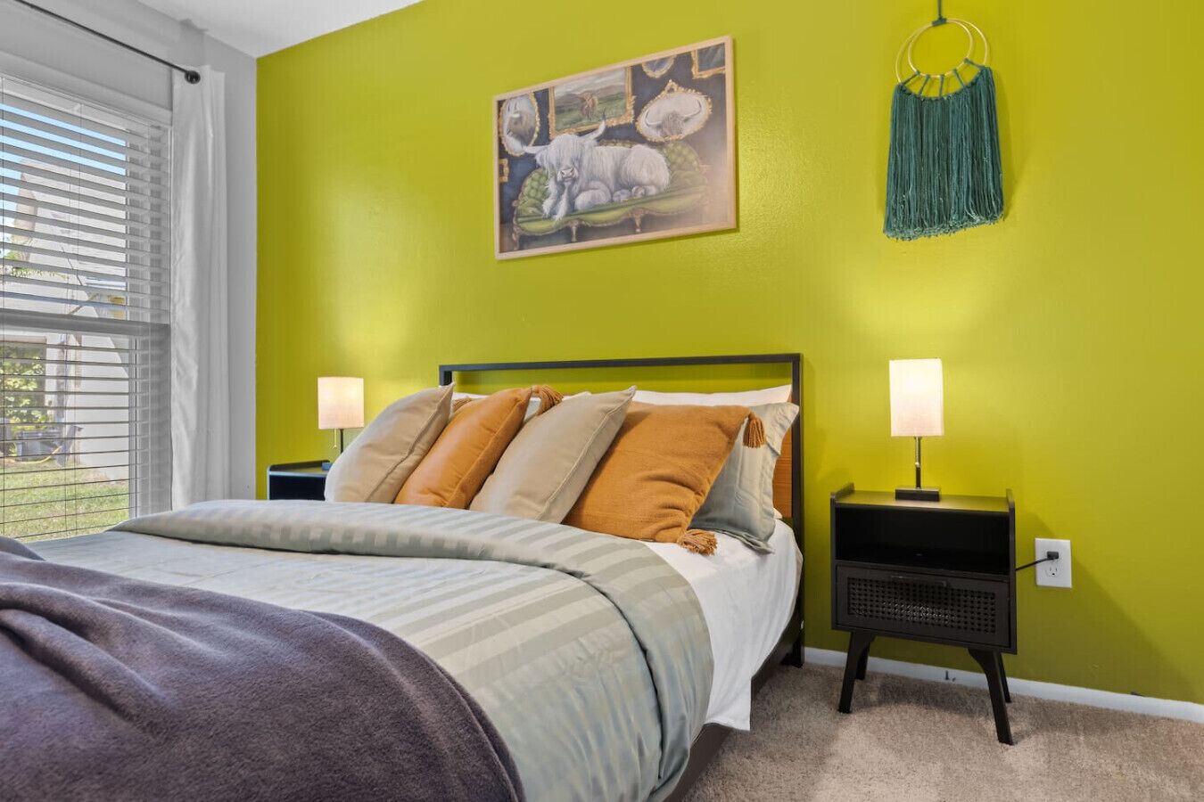 A bedroom with a bed, two bedside tables, a wall-mounted lamp, and a painting.