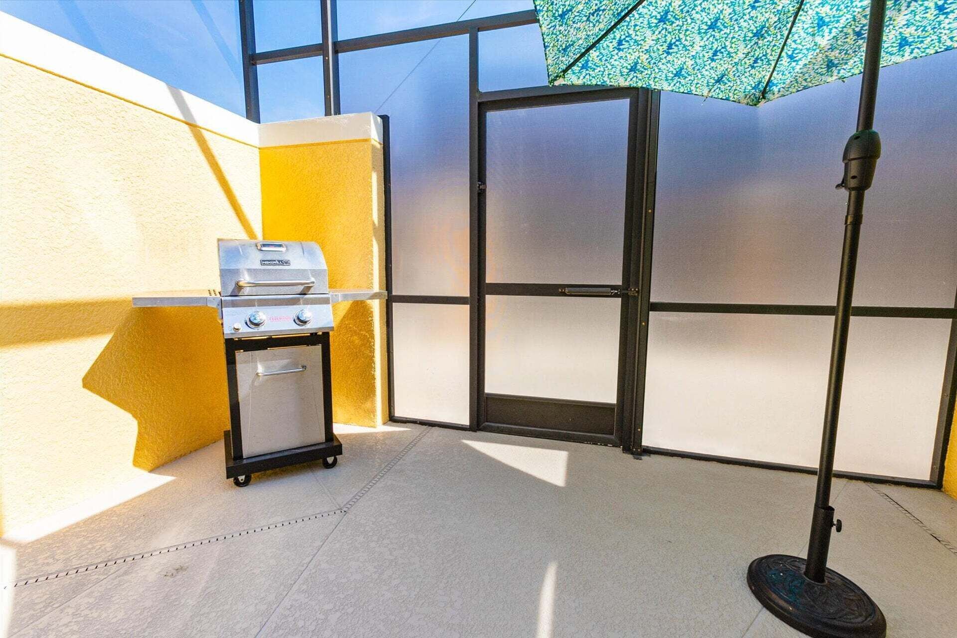 Una habitación con una parrilla, un carrito, una puerta y un poste con un paraguas estampado.