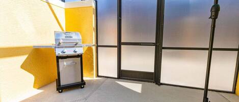 Una habitación con una parrilla, un carrito, una puerta y un poste con un paraguas estampado.