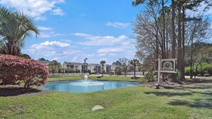 A residential area with a swimming pool, a fountain, and a sign indicating 'South'. - River Oaks 60N (Myrtle Beach)