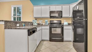 A kitchen with white cabinets, a black refrigerator, a microwave, and a stove. - River Oaks 60N (Myrtle Beach)