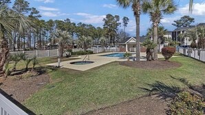 Zona residenziale con piscina, palme e giardino recintato.