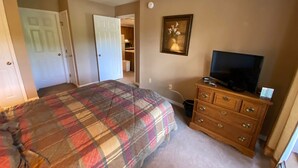 A bedroom with a bed, a dresser, a television, and a door leading to a closet. - Pico Village Resort D209 (Killington)