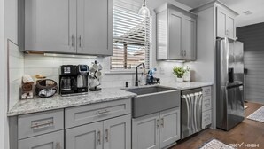 A modern kitchen with grey cabinets, stainless steel appliances, and a coffee maker.