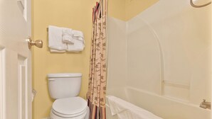A bathroom with a toilet, a bathtub, and a shower curtain. - River Oaks 7I (Myrtle Beach)