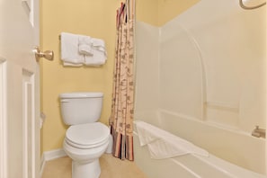 A bathroom with a toilet, a bathtub, and a shower curtain.