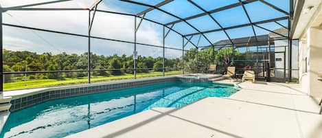 A covered outdoor swimming pool with a view of a green landscape.