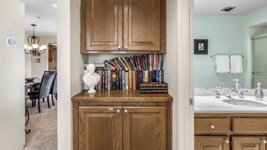 Una cocina con armarios de madera, encimera de mármol y una estantería llena de libros.