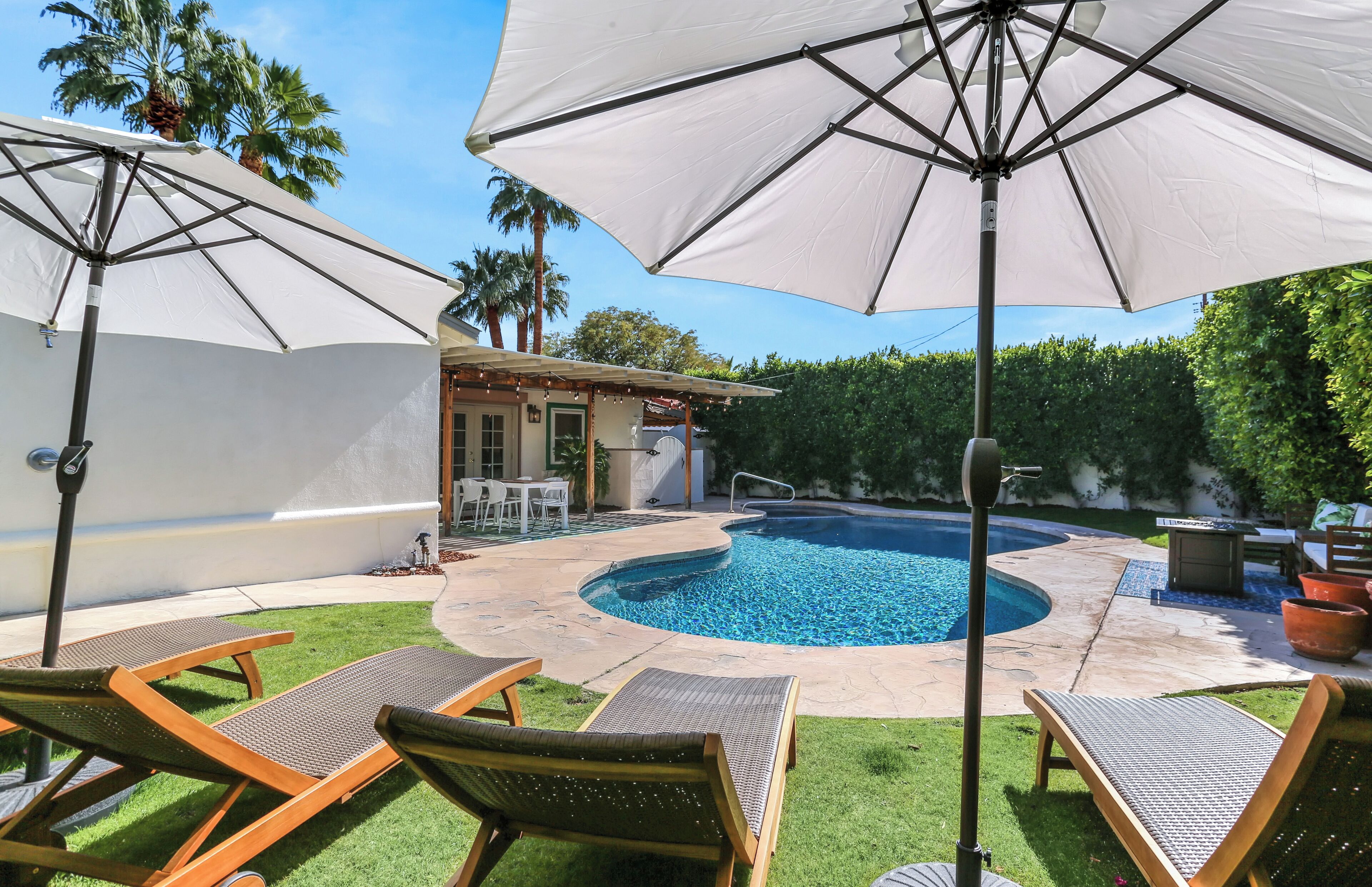Ein Garten mit Swimmingpool, Liegestühlen und Sonnenschirmen.