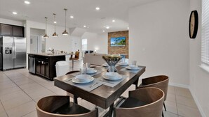 A modern kitchen with a built-in refrigerator, a dining area with a wooden table set for four, and a living room with a sofa and a television mounted on the wall. - Smm1811 (Davenport)