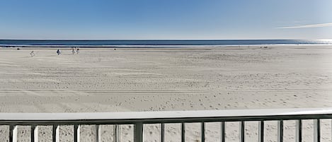 A beach with a wooden railing in the foreground.