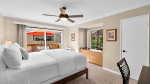Un dormitorio con cama, ventilador de techo, cómoda y ventana con vistas al exterior.