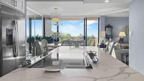 A modern kitchen with a marble countertop, stainless steel appliances, and a view to the outdoors. - Sandy Cove (Siesta Key)