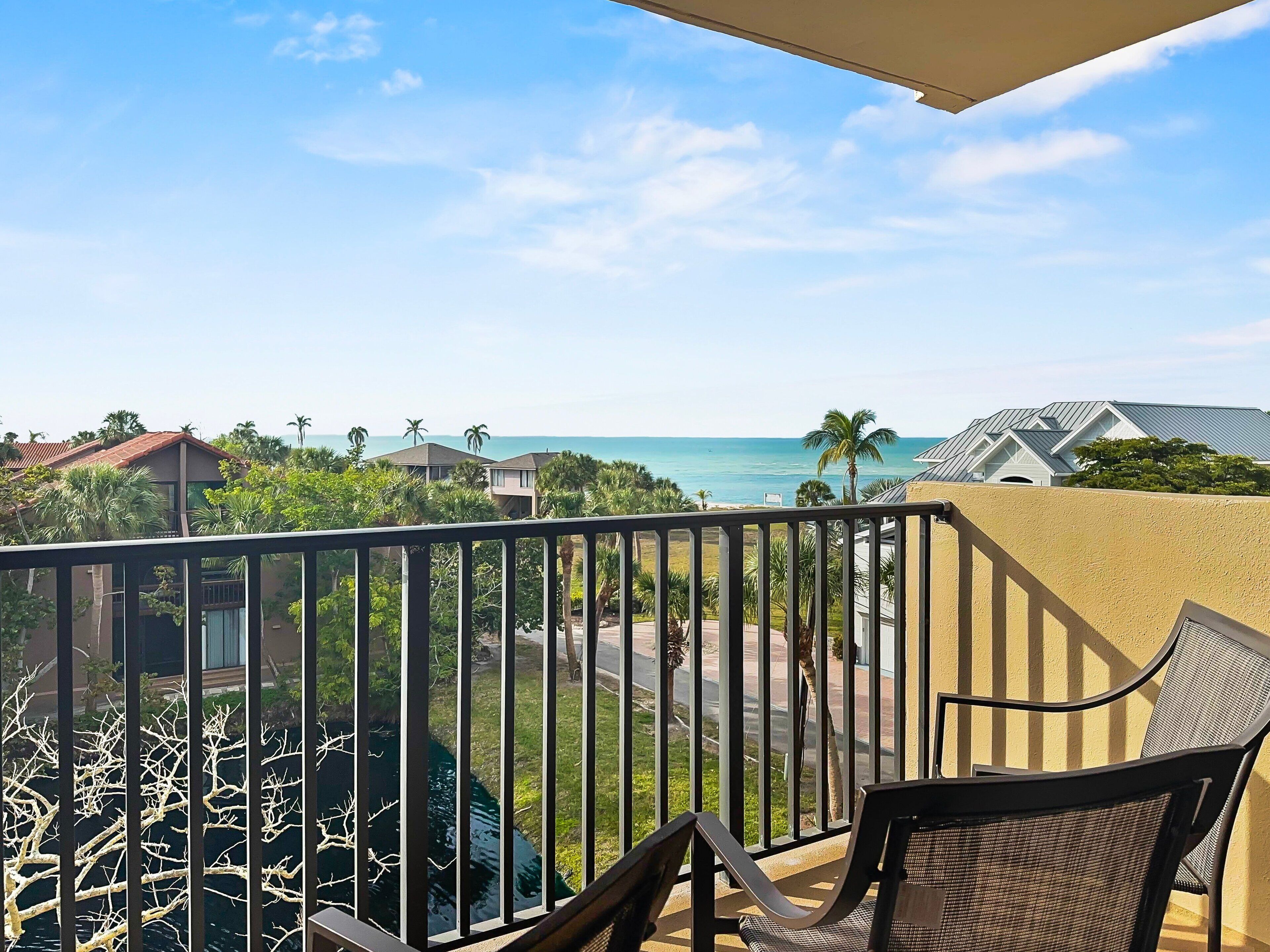 A balcony with a view of the ocean and palm trees.