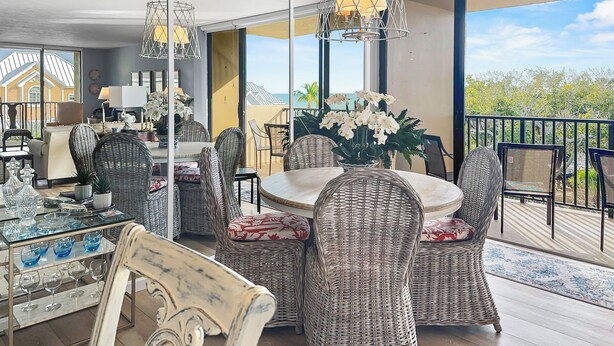 A spacious balcony with wicker furniture and a glass table, overlooking a scenic view. - Sandy Cove (Siesta Key)