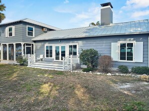 A two-story house with a covered porch, a chimney, and a small garden area. - Sandy Cove (Siesta Key)