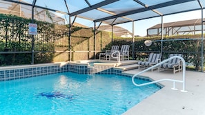 A pool area with a glass enclosure, lounge chairs, and a sign indicating pool rules. - Sp8136 (Kissimmee)