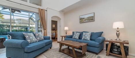 A modern living room with two blue sofas, a wooden coffee table, and two lamps.