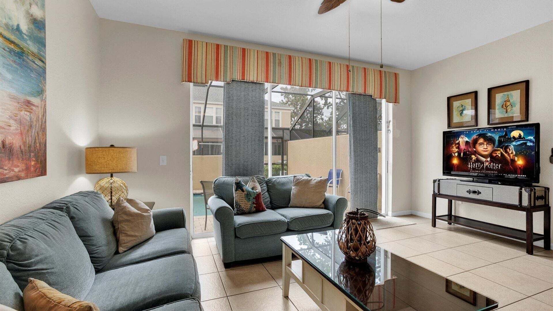 A living room with a sofa, a coffee table, a TV, and a painting on the wall.