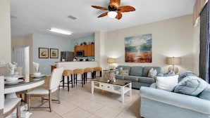 A living room with a dining area, a ceiling fan, a painting, and a kitchen in the background. - Skc7653 (Kissimmee)