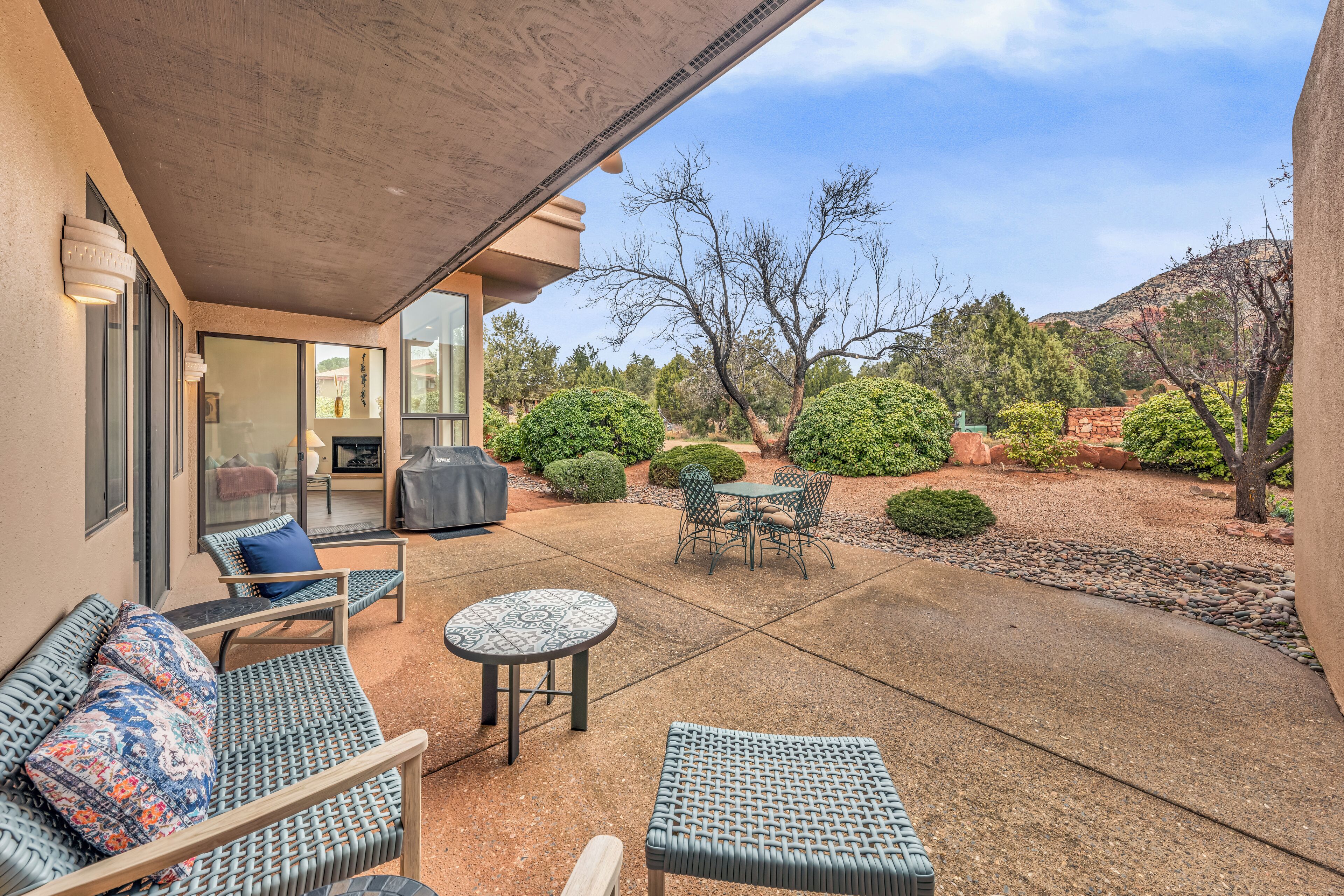 An outdoor patio with wicker furniture, a small round table, and a grill.