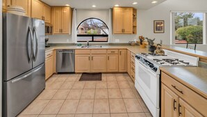 A modern kitchen with wooden cabinets, stainless steel appliances, and a large window offering a view of the outdoors. - Santa Susana (Sedona)