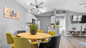 A modern dining area with a round table, yellow and black chairs, a potted plant, and a contemporary chandelier.