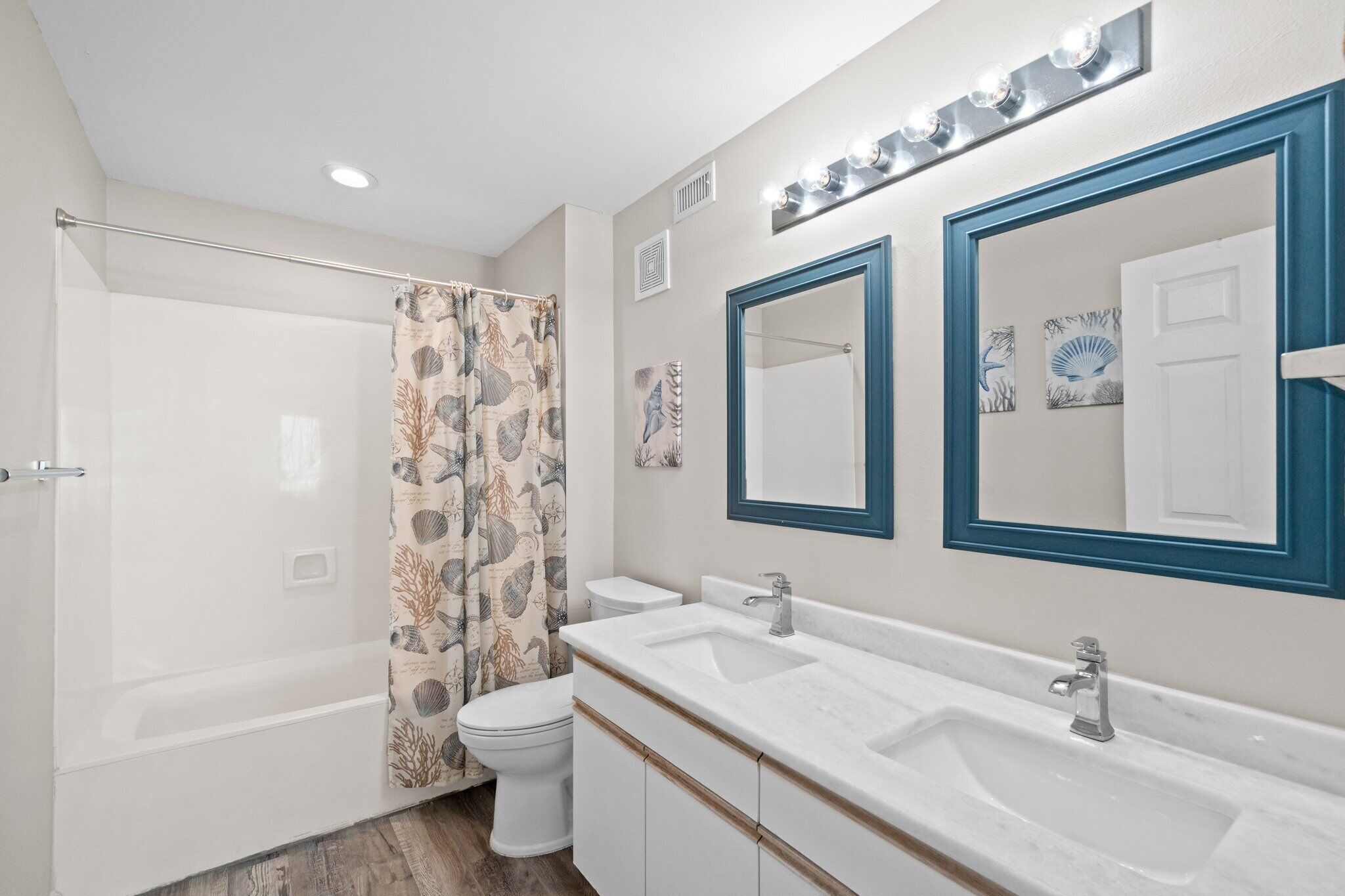 A bathroom with a shower, toilet, and double sink with vanity.