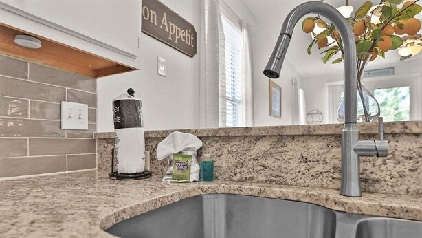 Eine Küche mit einer Granitabdeckung, einer Edelstahlspüle und einem modernen Wasserhahn.